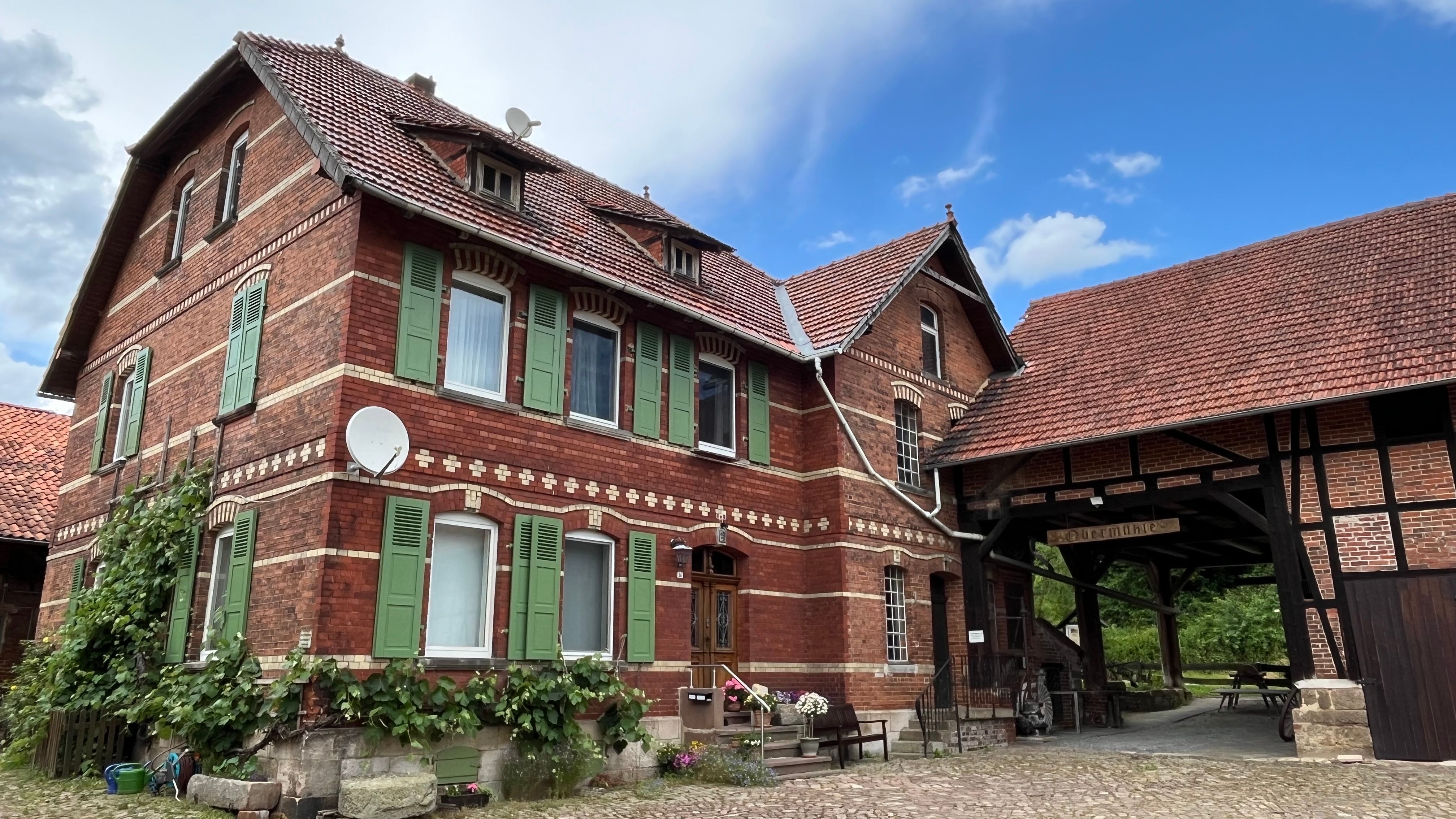 Historische Obermühle Wilhelmshausen mit grünen Fensterläden und angrenzender Scheune